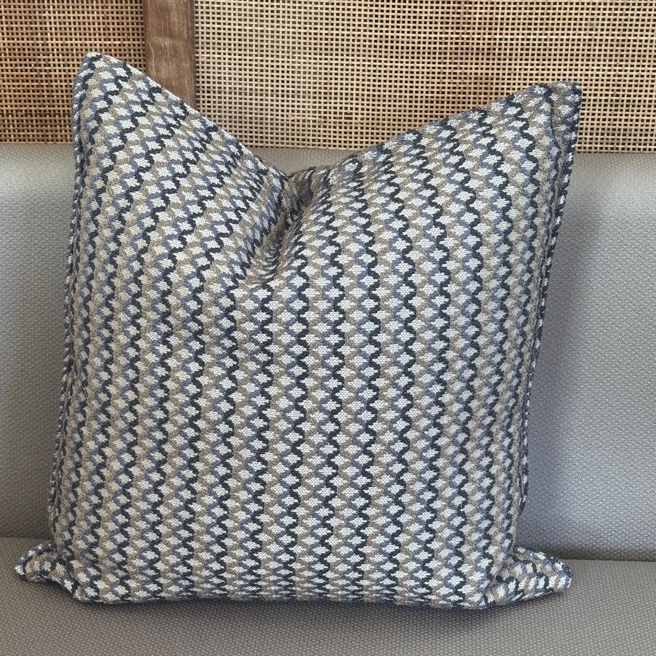 Coussin décoratif à rayures irrégulières taupes, bleus posé sur un canapé