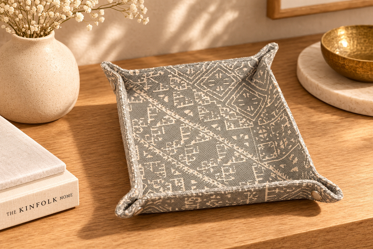 Vide-poche décoratif en tissu marocain tissé gris et écru à motifs géométriques, posé sur une console en bois dans une ambiance chaleureuse – Biyadi Collection.