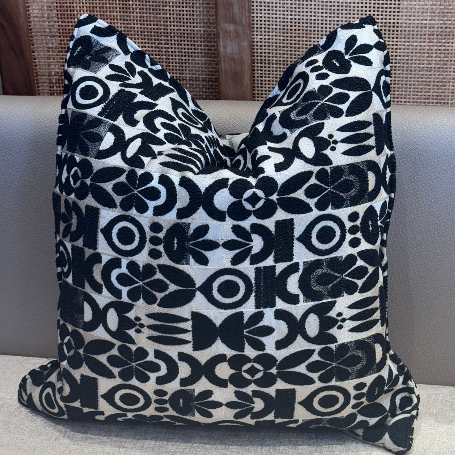 Coussin décoratif noir avec motif floral graphique blanc, design moderne et élégant pour salon ou chambre.