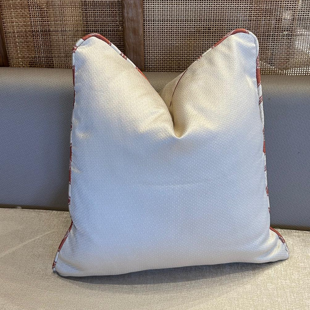 Coussin décoratif uni ivoire avec passepoil en tissu ethnique marocain, finition haut de gamme.