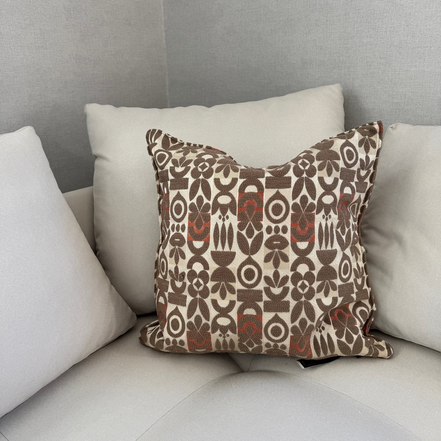 Coussin beige à motif floral géométrique en tissu bouclette, idéal pour décoration de salon moderne et élégante