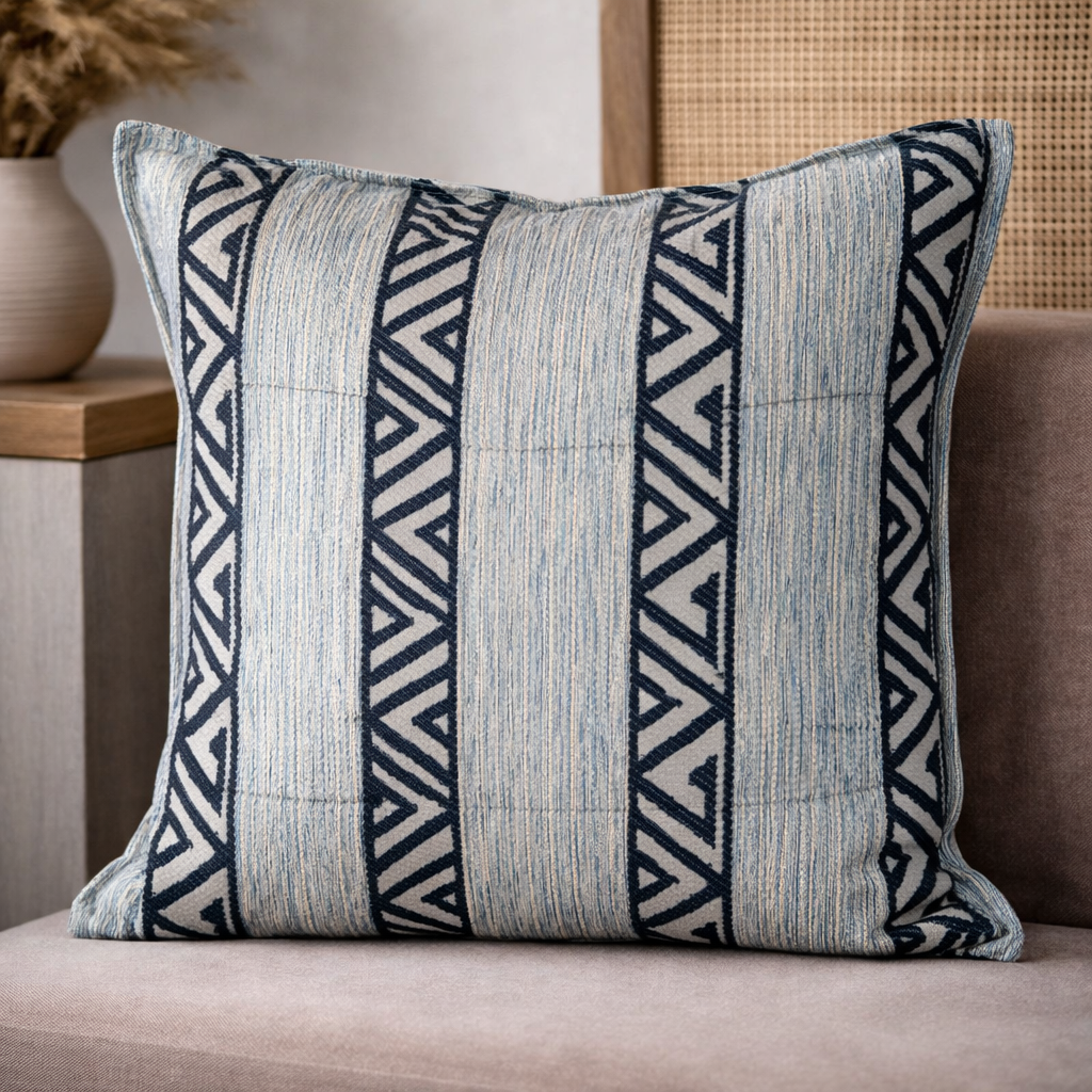 Coussin décoratif en tissu tissé bleu à bandes verticales et motif zigzag, présenté dans une ambiance douce et contemporaine.
