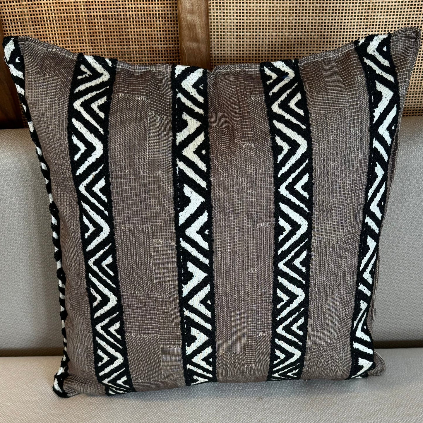 Coussin décoratif marron à rayures ethniques noires et écrues avec motifs géométriques tissés, idéal pour une décoration moderne et chaleureuse.
