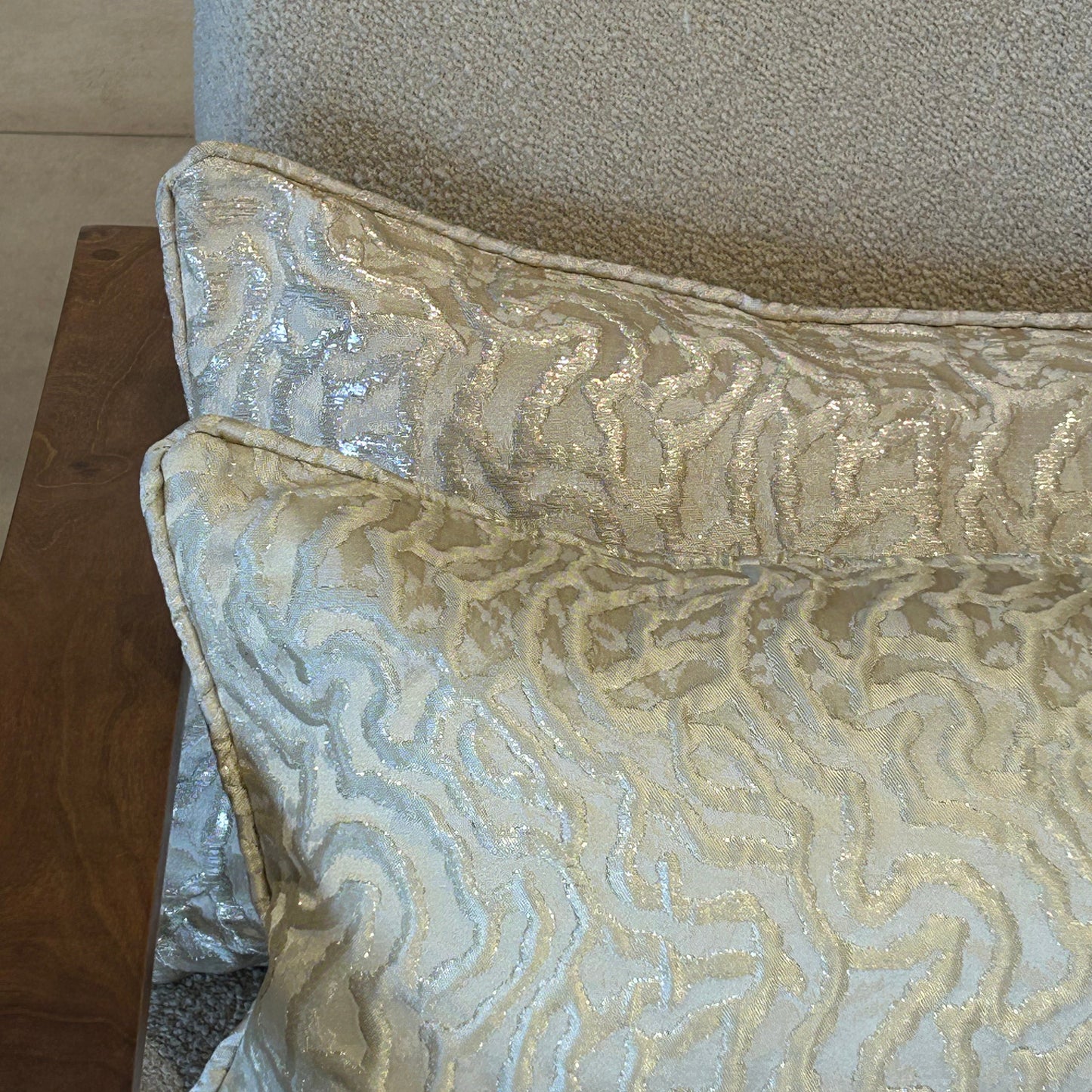 Détail d’un coussin beige à motif organique texturé avec reflets lumineux, finition soignée