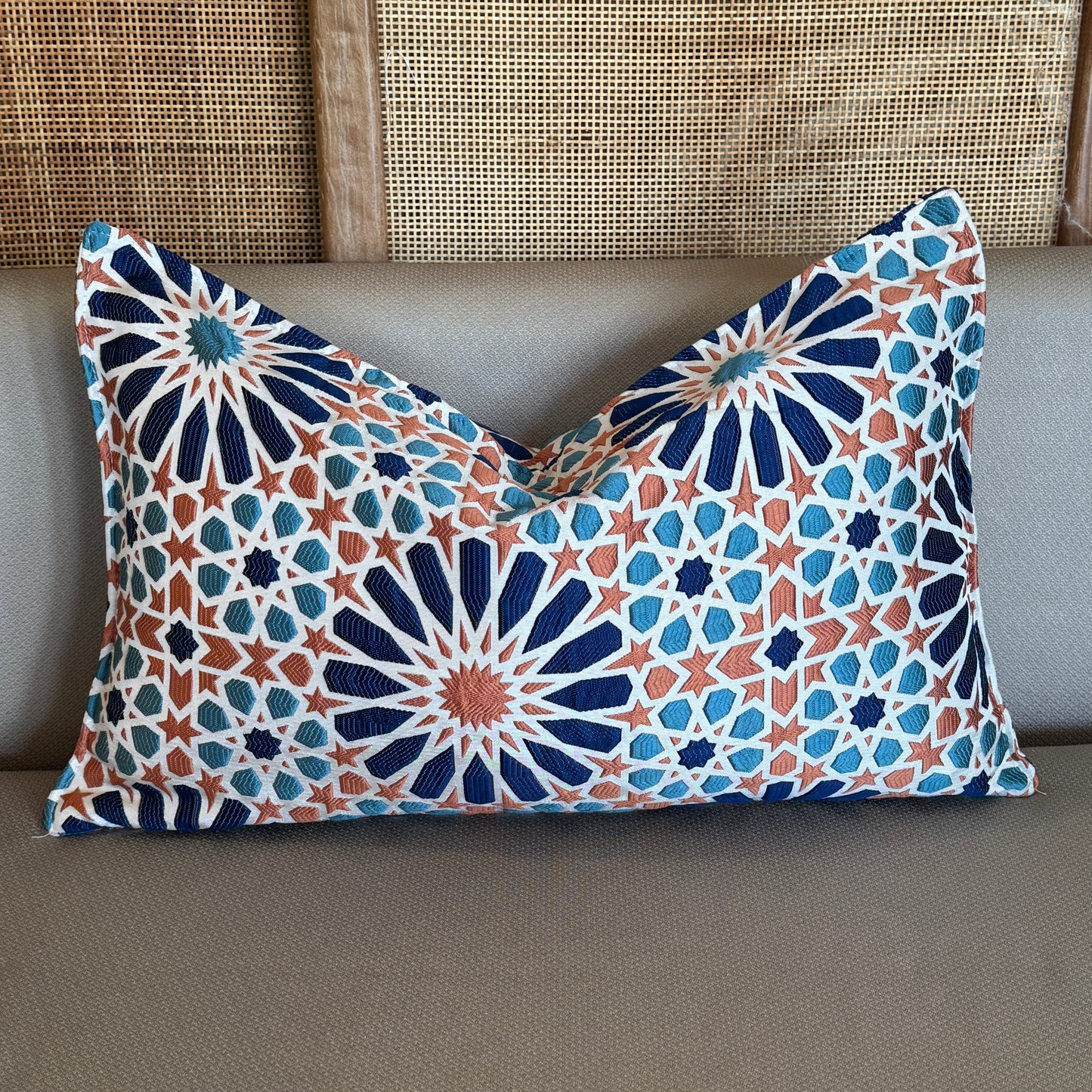 Coussin rectangulaire décoratif en tissu tissé marocain à motif zellij, teintes bleu, terracotta et écru, présenté sur canapé dans une ambiance élégante et contemporaine.