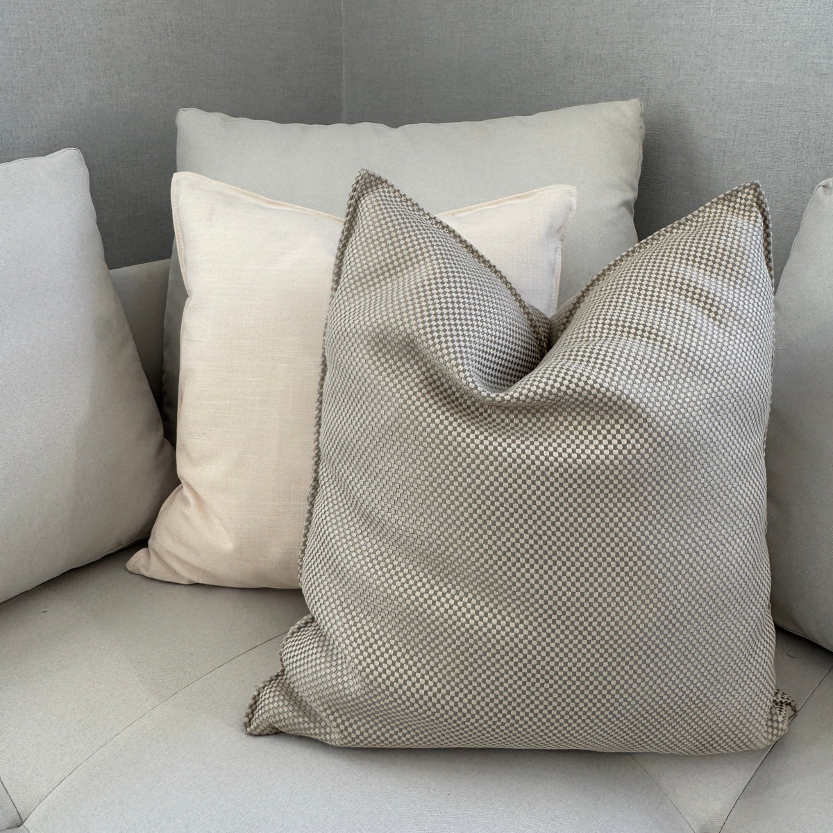 Coussin décoratif beige en tissu tissé à texture fine, idéal pour un salon moderne et une décoration intérieure haut de gamme