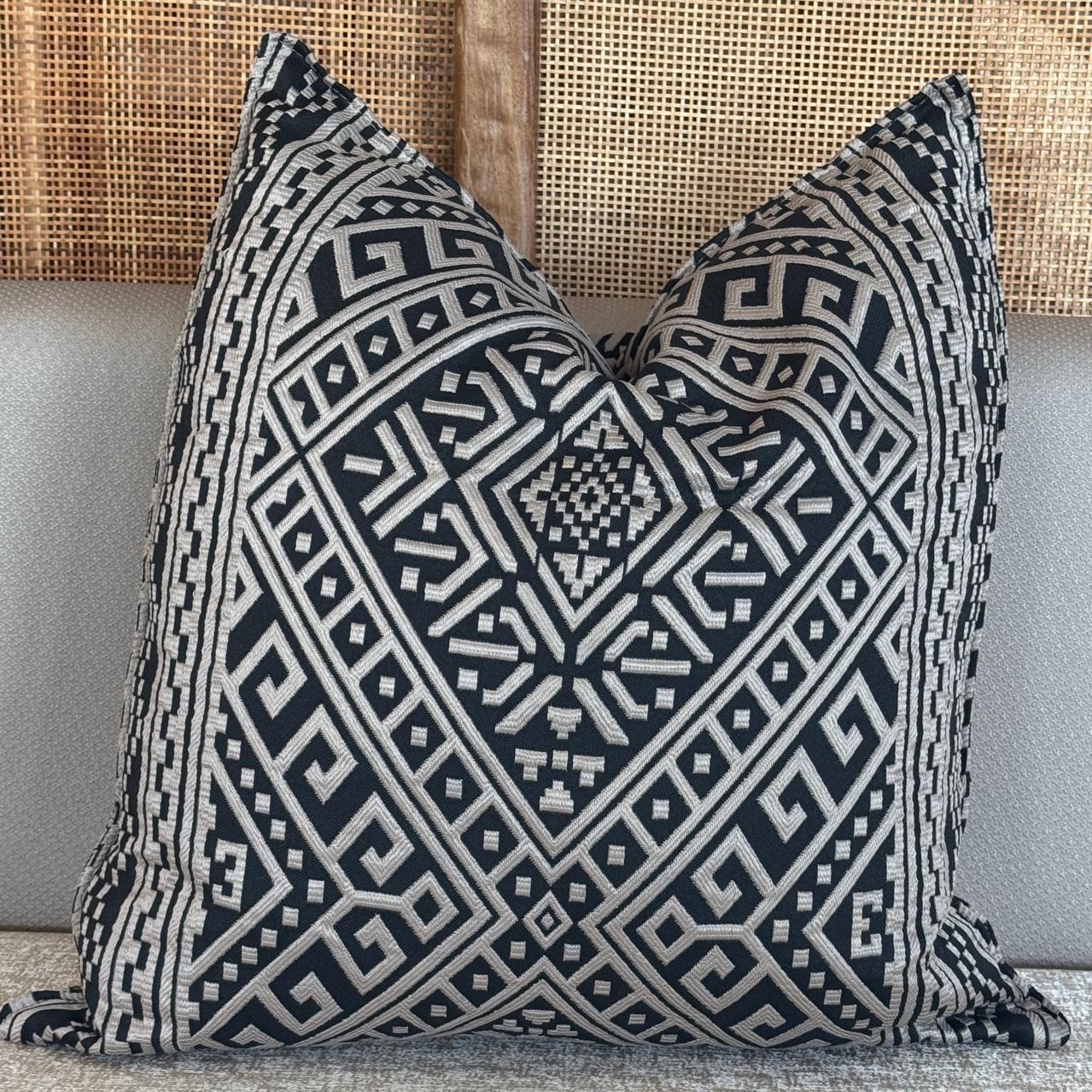Coussin décoratif noir et sable à motif géométrique tissé en relief, de style ethnique chic.