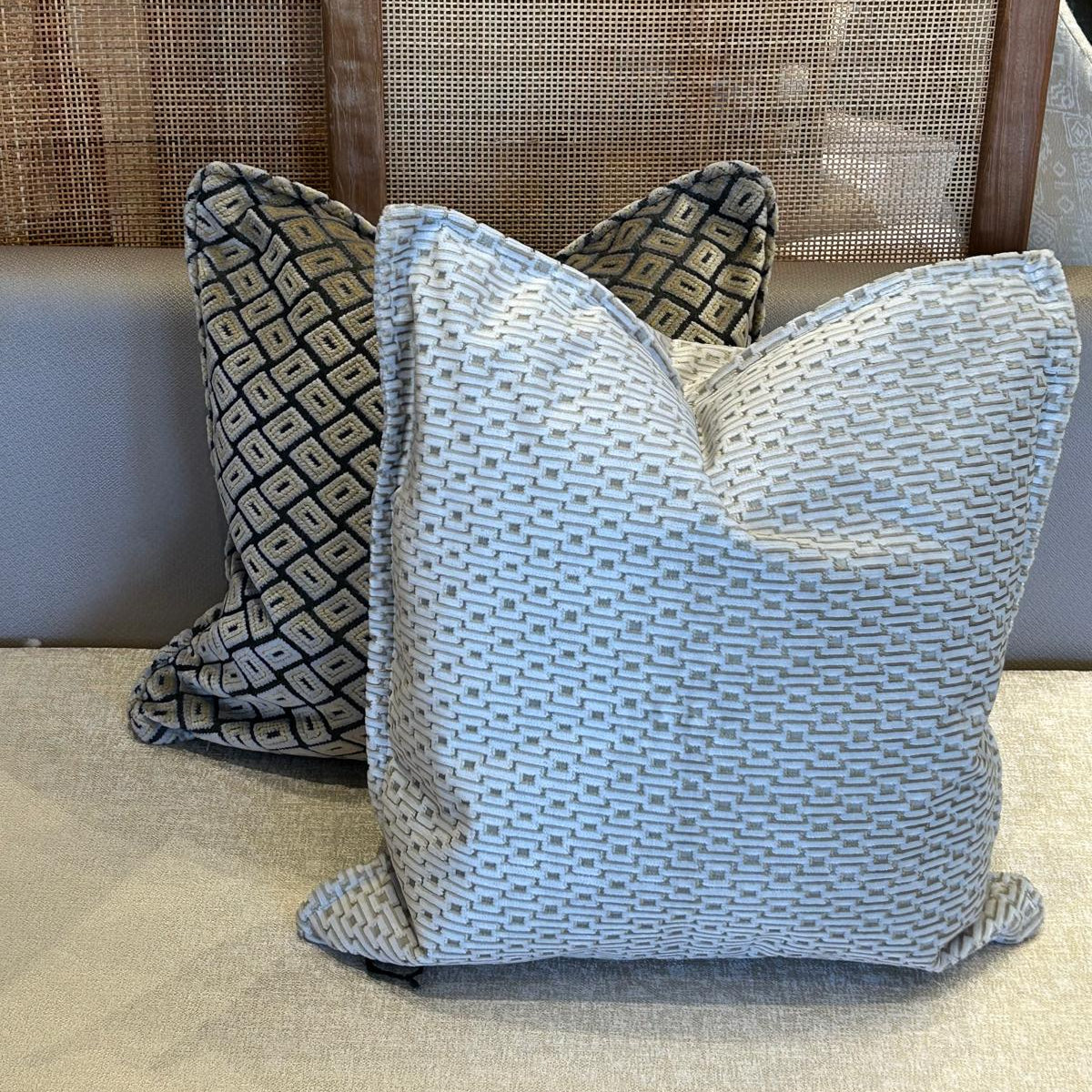 oussins décoratifs en tissus tissés en relief, association d’un coussin ethnique géométrique et d’un coussin uni ivoire élégant.
