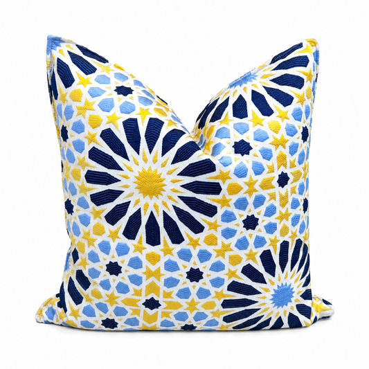 Coussin décoratif bleu, jaune et bleu clair à grand motif inspiré du zellij marocain sur fond blanc.