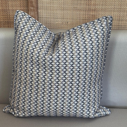 Coussin décoratif à rayures irrégulières taupes, bleus posé sur un canapé