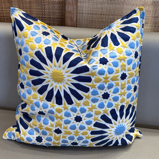 Coussin décoratif en tissu marocain tissé en relief, motif zellige bleu, jaune et blanc, posé sur canapé
