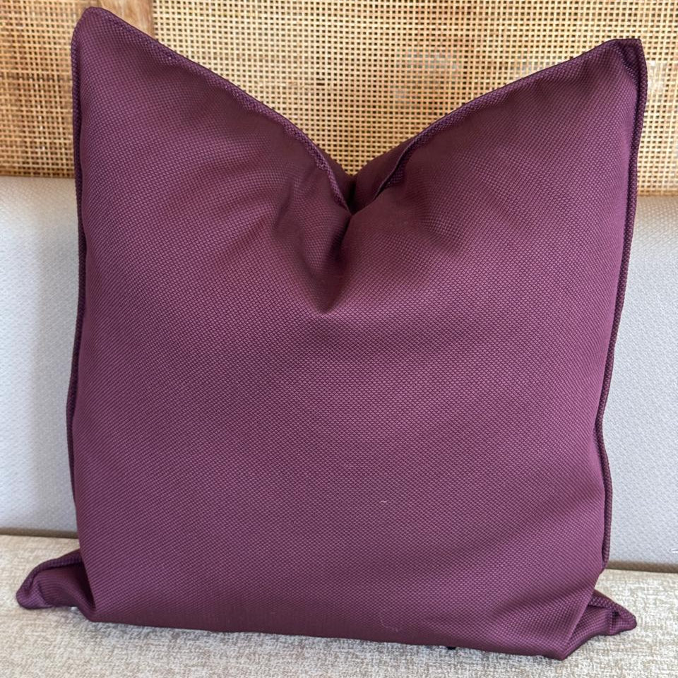 Coussin décoratif uni couleur burgundy en tissu marocain, style moderne et élégant, posé sur un canapé.