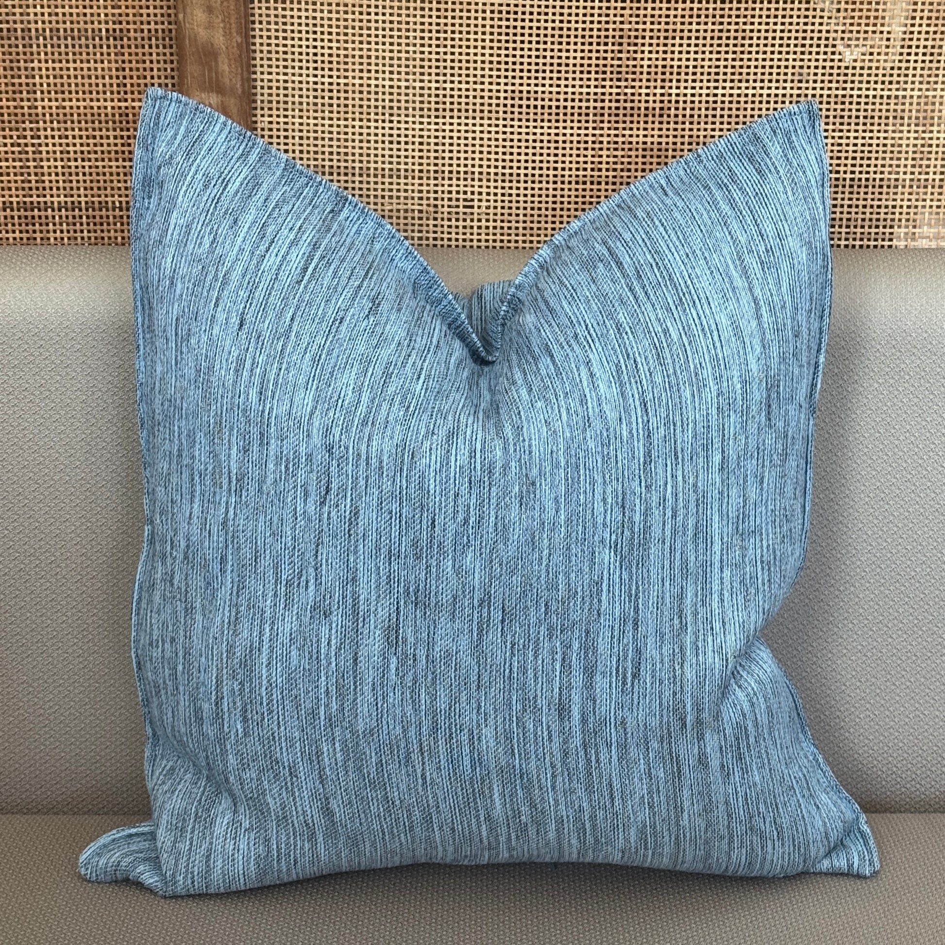 Coussin décoratif bleu texturé avec fines lignes verticales, apportant une touche moderne et apaisante à la décoration intérieure.
