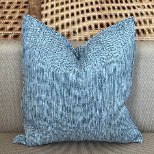 Coussin décoratif bleu texturé avec fines lignes verticales, apportant une touche moderne et apaisante à la décoration intérieure.