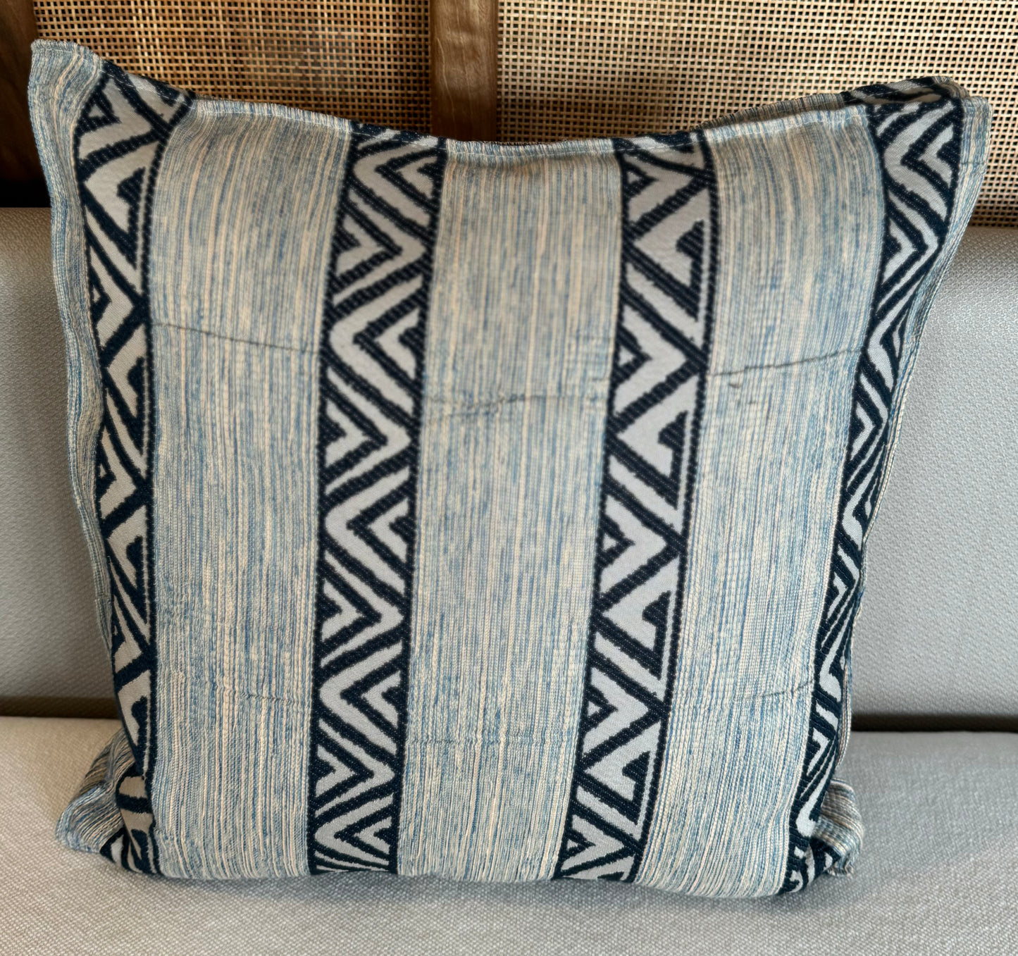 Coussin décoratif en tissu tissé à bandes verticales bleu clair et motifs zigzag bleu foncé, au style graphique et contemporain.