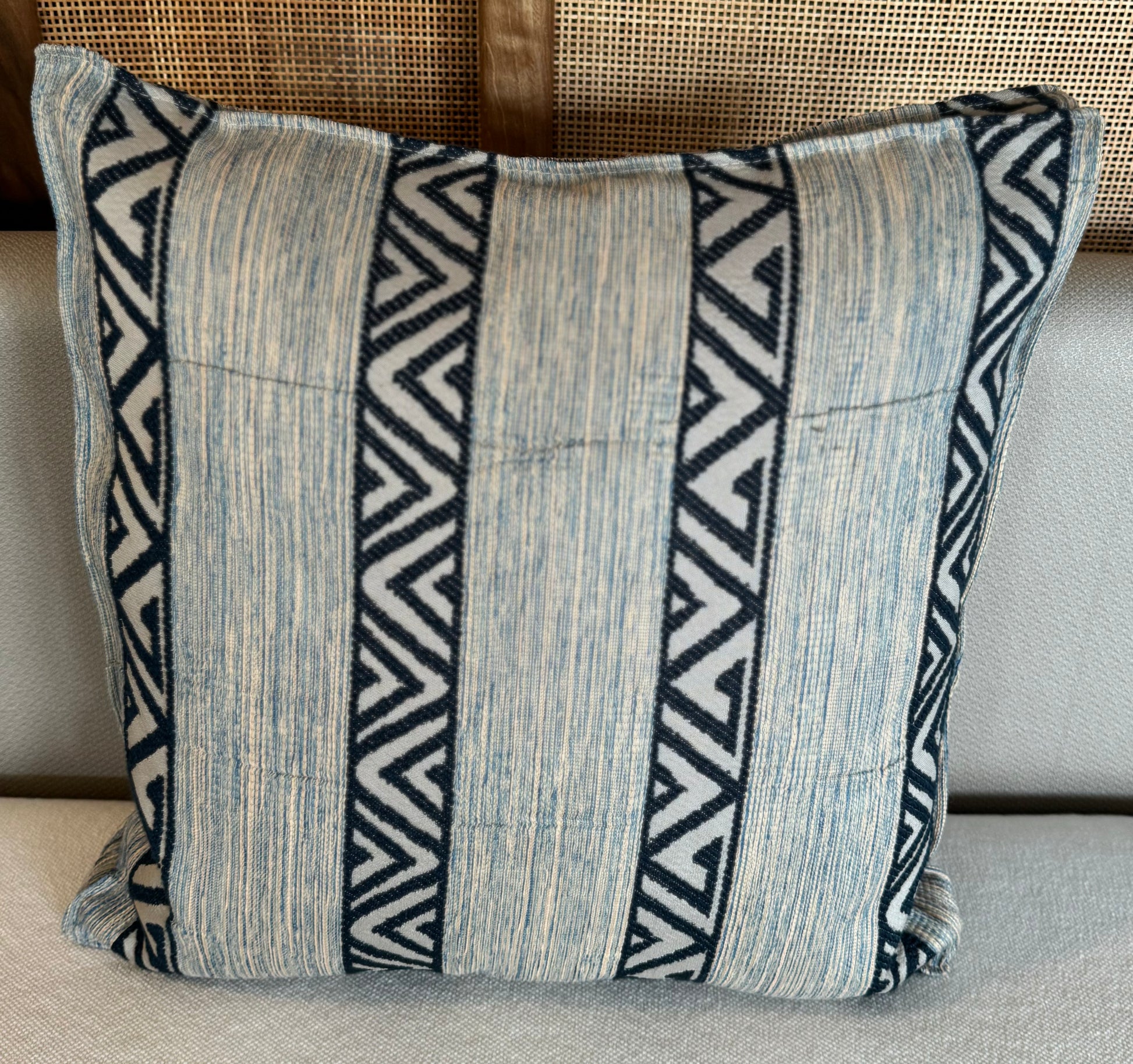 Coussin décoratif en tissu tissé à bandes verticales bleu clair et motifs zigzag bleu foncé, au style graphique et contemporain.
