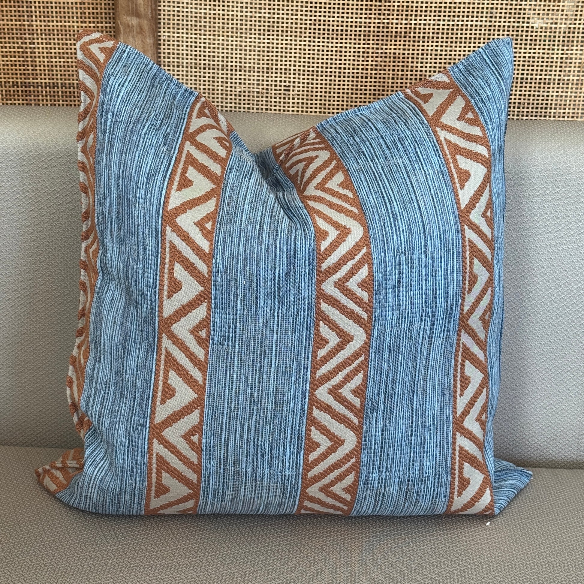 Coussin décoratif bleu et brun à bandes verticales et motifs géométriques ethniques, apportant une touche bohème et chaleureuse à la décoration intérieure