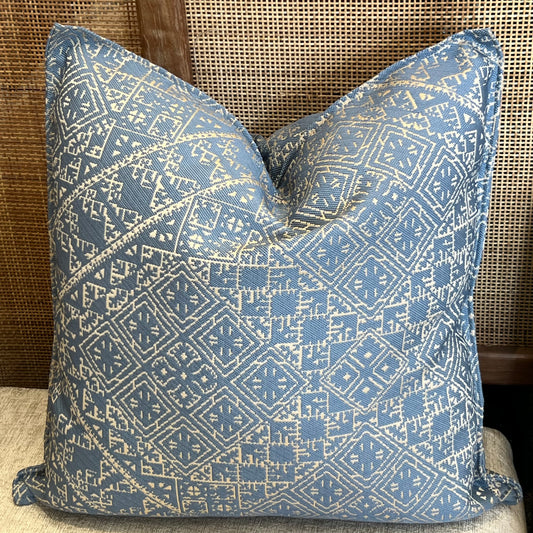 Coussin décoratif ethnique bleu  à motifs géométriques blancs, tissu tissé en relief, style élégant et moderne.
