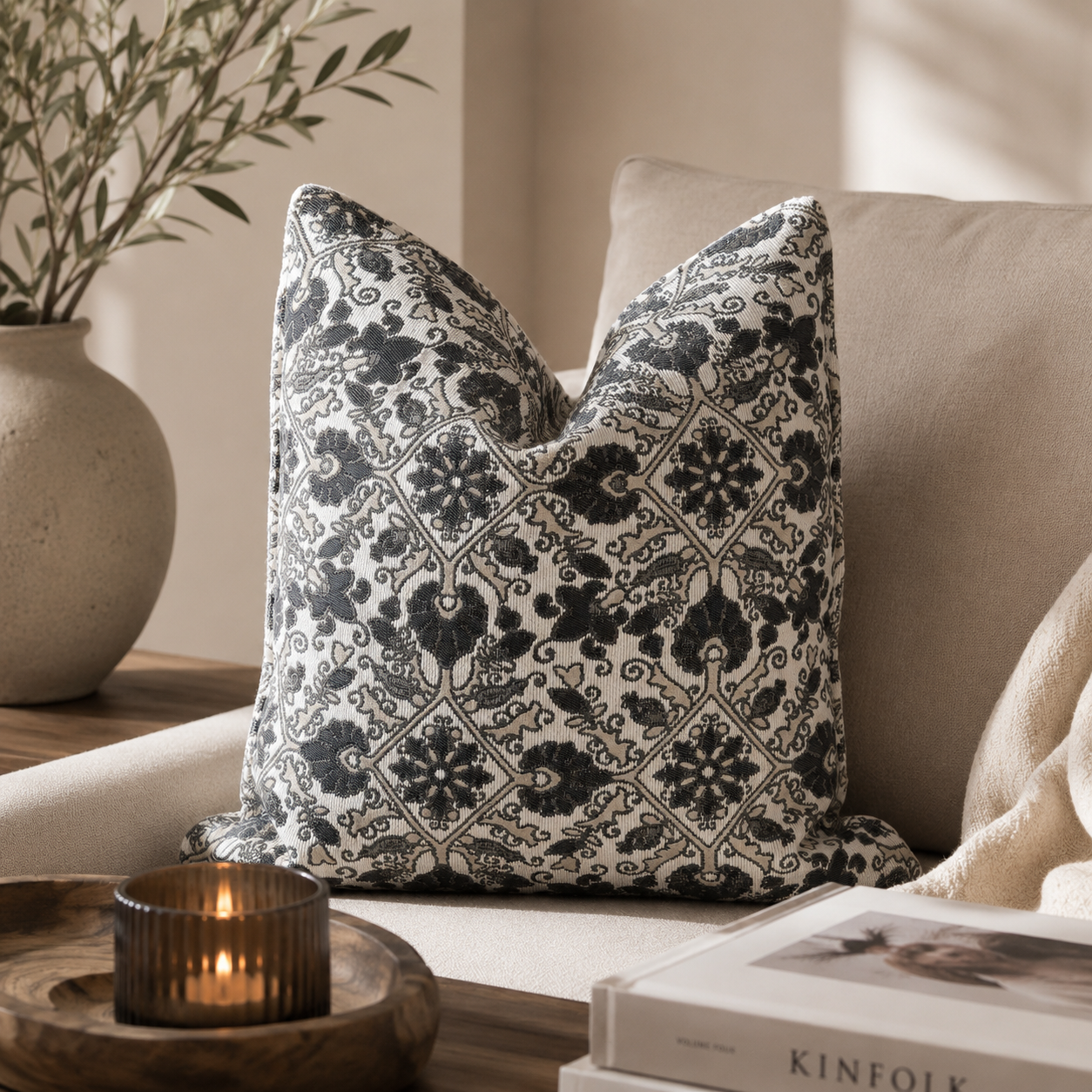 Coussin décoratif gris et blanc à motifs arabesques dans un salon chic et lumineux avec décoration naturelle et ambiance chaleureuse.