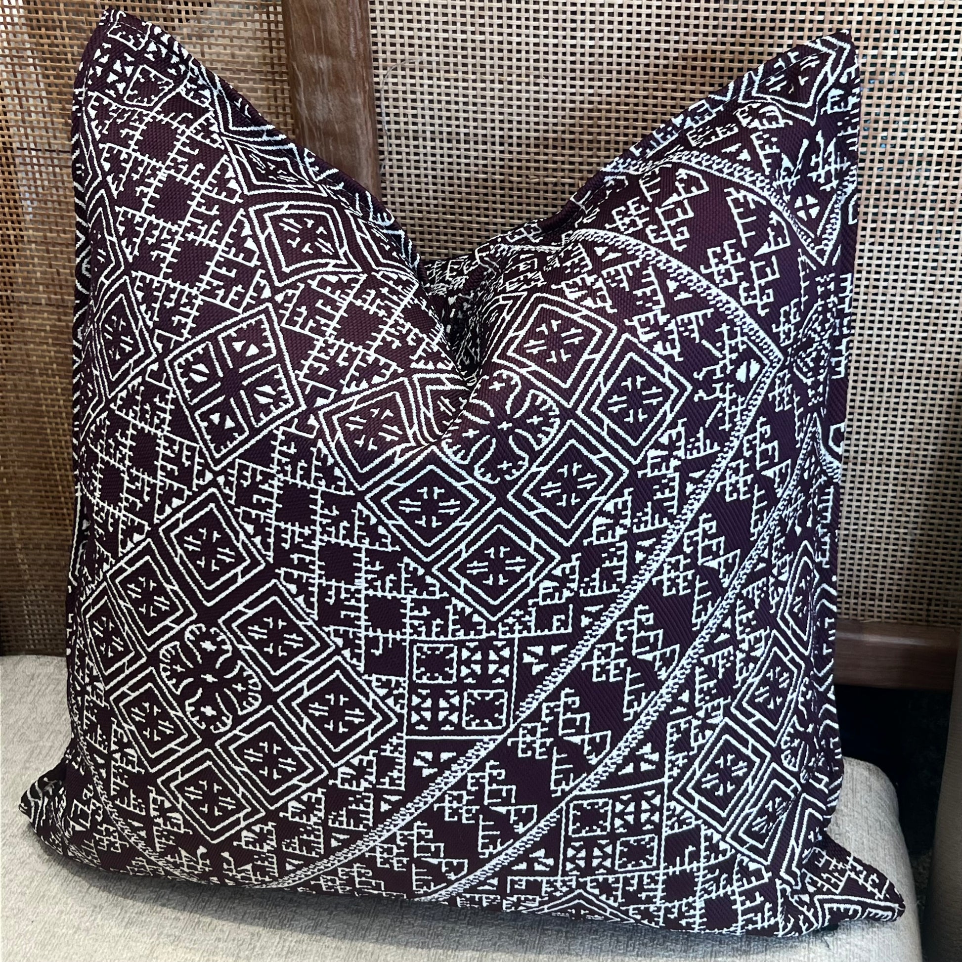 Coussin decoratif carre à motif tarz geometrique marocain burgundy et ecru, tisse en relief, mis en scene dans un salon elegant et chaleureux