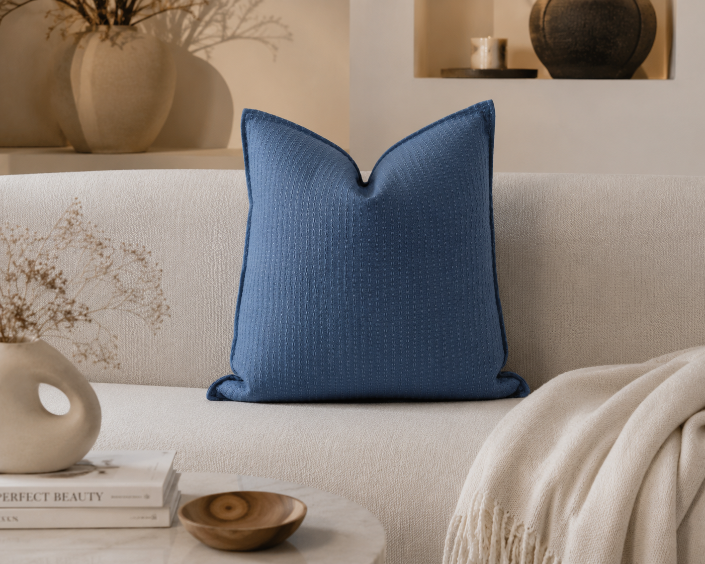 Coussin décoratif bleu à texture discrète en relief, présenté dans une ambiance intérieure chic et apaisante avec canapé beige et décoration minimaliste.