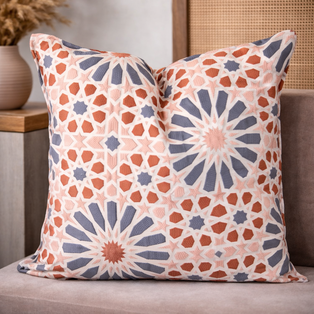 Coussin décoratif à motif géométrique zellij en tissu tissé , tons rose poudré, terracotta et gris, mis en scène sur un canapé dans une ambiance chaleureuse et élégante.