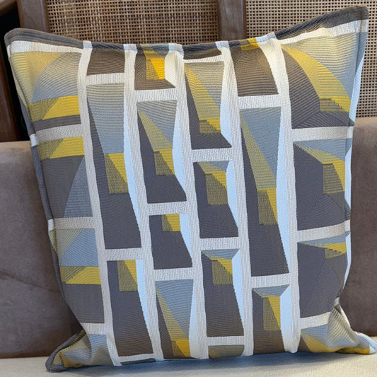 Coussin décoratif en tissu tissé à motif graphique géométrique, teintes taupes t jaunes .
