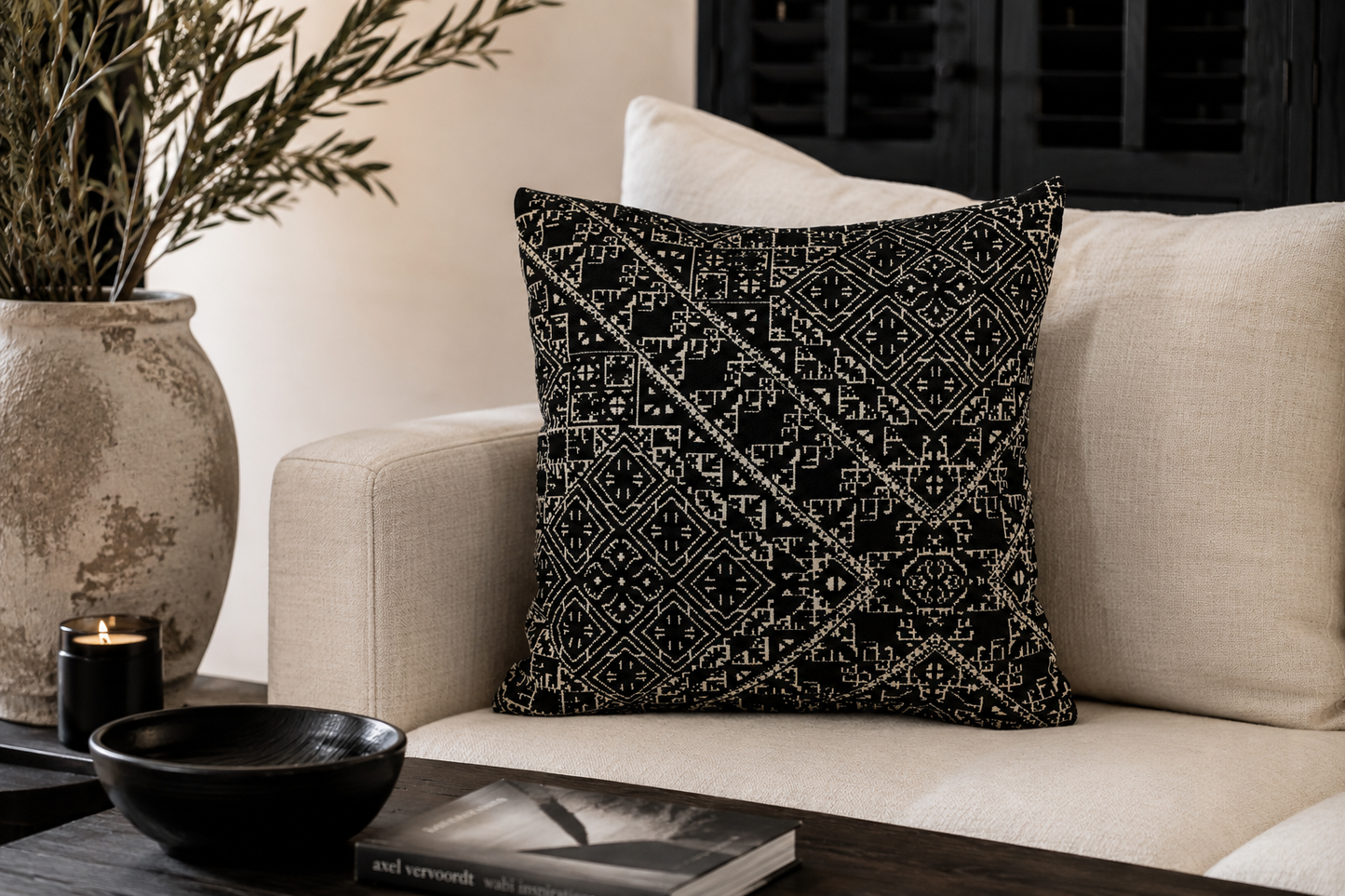 Coussin marocain tarz noir et blanc à motifs géométriques dans un salon moderne néobeldi avec canapé beige et décoration élégante.