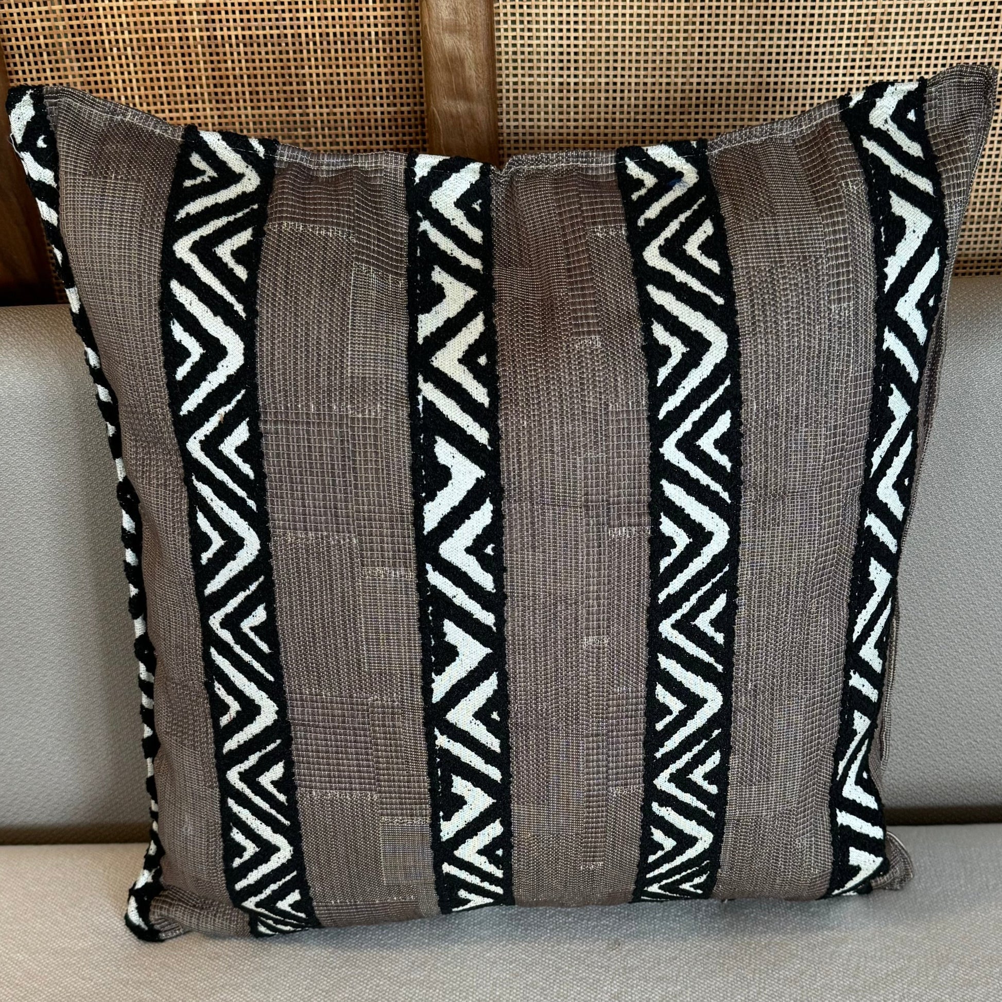 Coussin décoratif marron à rayures ethniques noires et écrues avec motifs géométriques tissés, idéal pour une décoration moderne et chaleureuse.