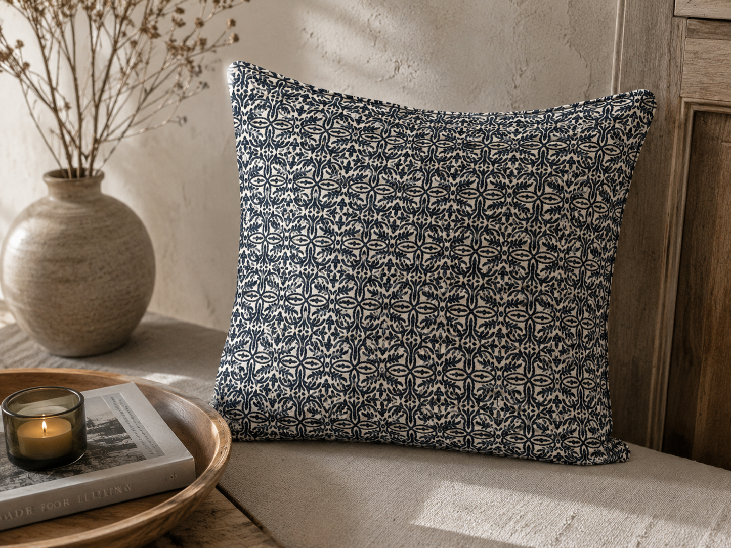 Coussin décoratif bleu et écru à motif floral géométrique dans une ambiance chaleureuse et élégante avec décoration naturelle et bois.
