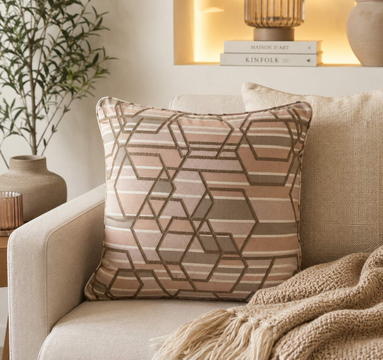 Coussin décoratif géométrique taupe et rose poudré dans une ambiance moderne et élégante aux tons naturels.