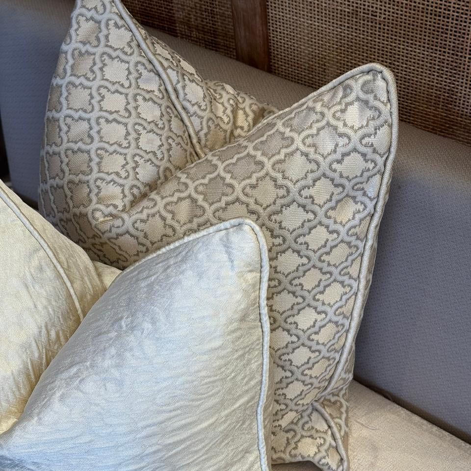 Composition de coussins décoratifs avec coussin à motif géométrique écru et beige tissé en relief, style élégant et harmonieux pour salon chic.