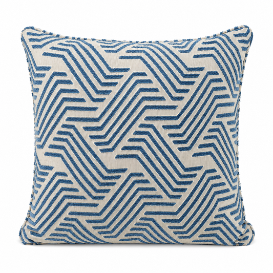 Coussin décoratif bleu et écru à motif graphique géométrique en relief sur fond blanc, style moderne et élégant pour décoration intérieure.