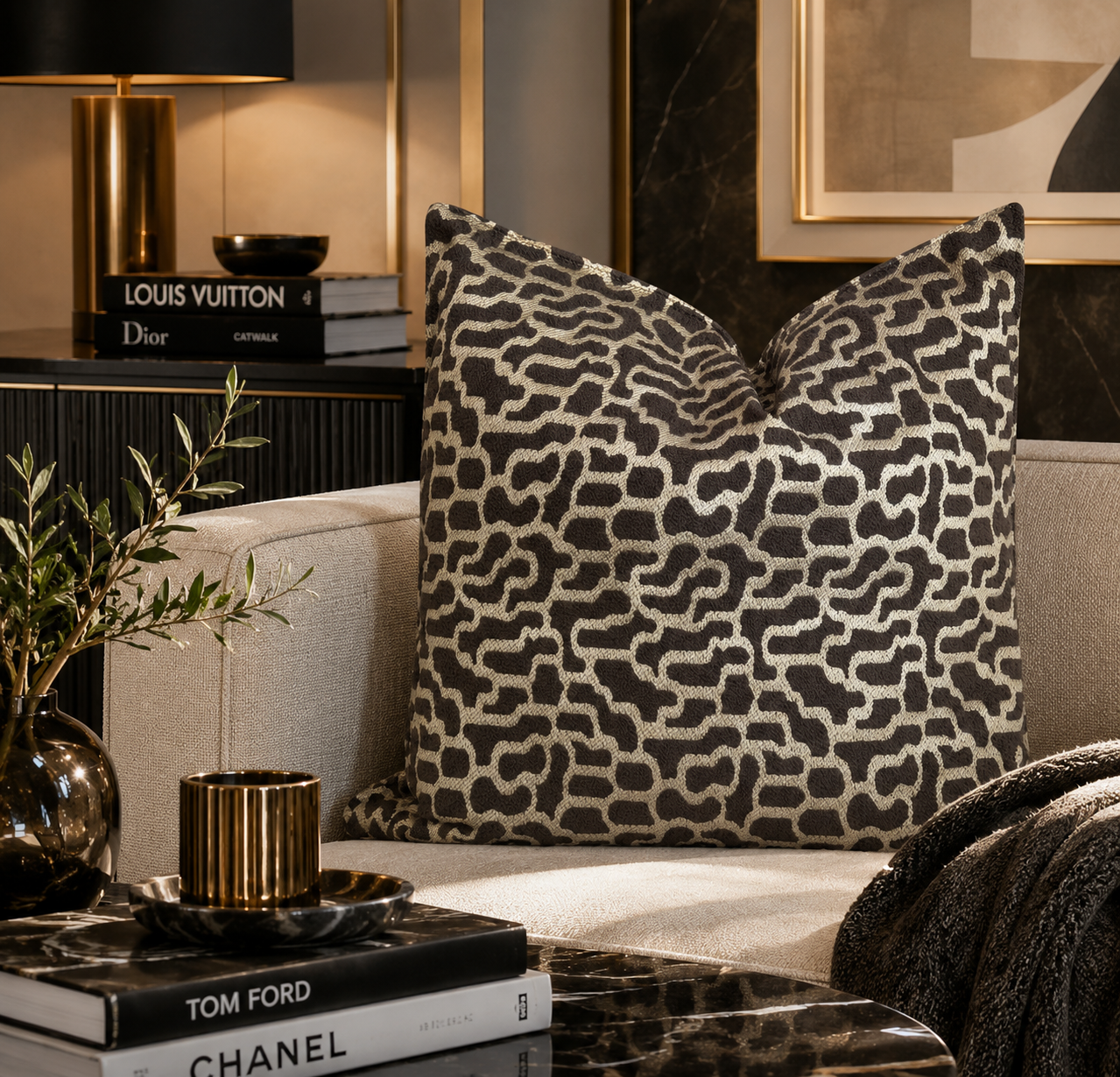 Coussin décoratif taupe et beige à motif abstrait dans un salon moderne  avec décoration contemporaine et détails noirs et dorés