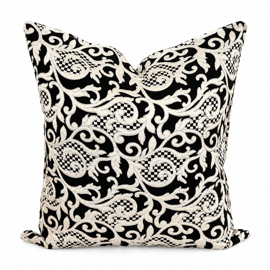Coussin décoratif noir et écru à motif arabesque brodé en relief sur fond blanc, style élégant et raffiné pour salon moderne.