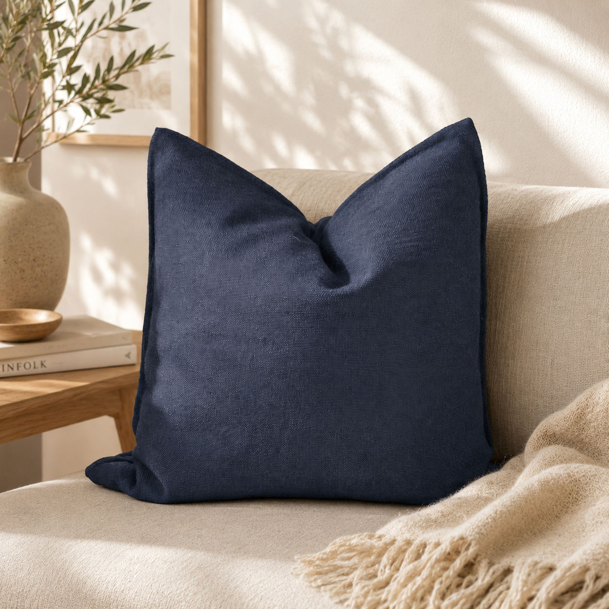 Coussin décoratif uni noir texturé posé sur un canapé beige dans une ambiance élégante et lumineuse aux tons naturels.