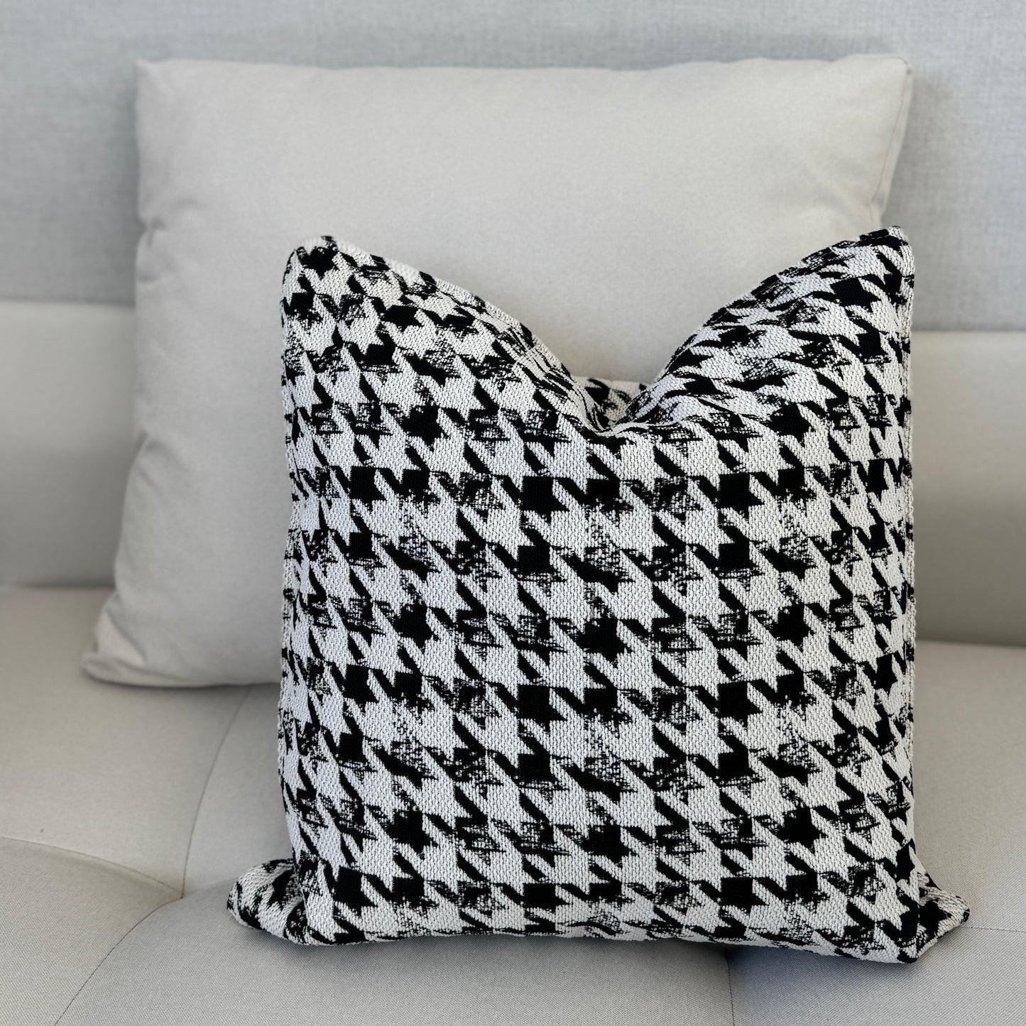 Coussin décoratif noir et blanc à motif pied-de-poule, tissu texturé tissé en relief, posé sur canapé moderne dans une ambiance épurée – Biyadi Collection