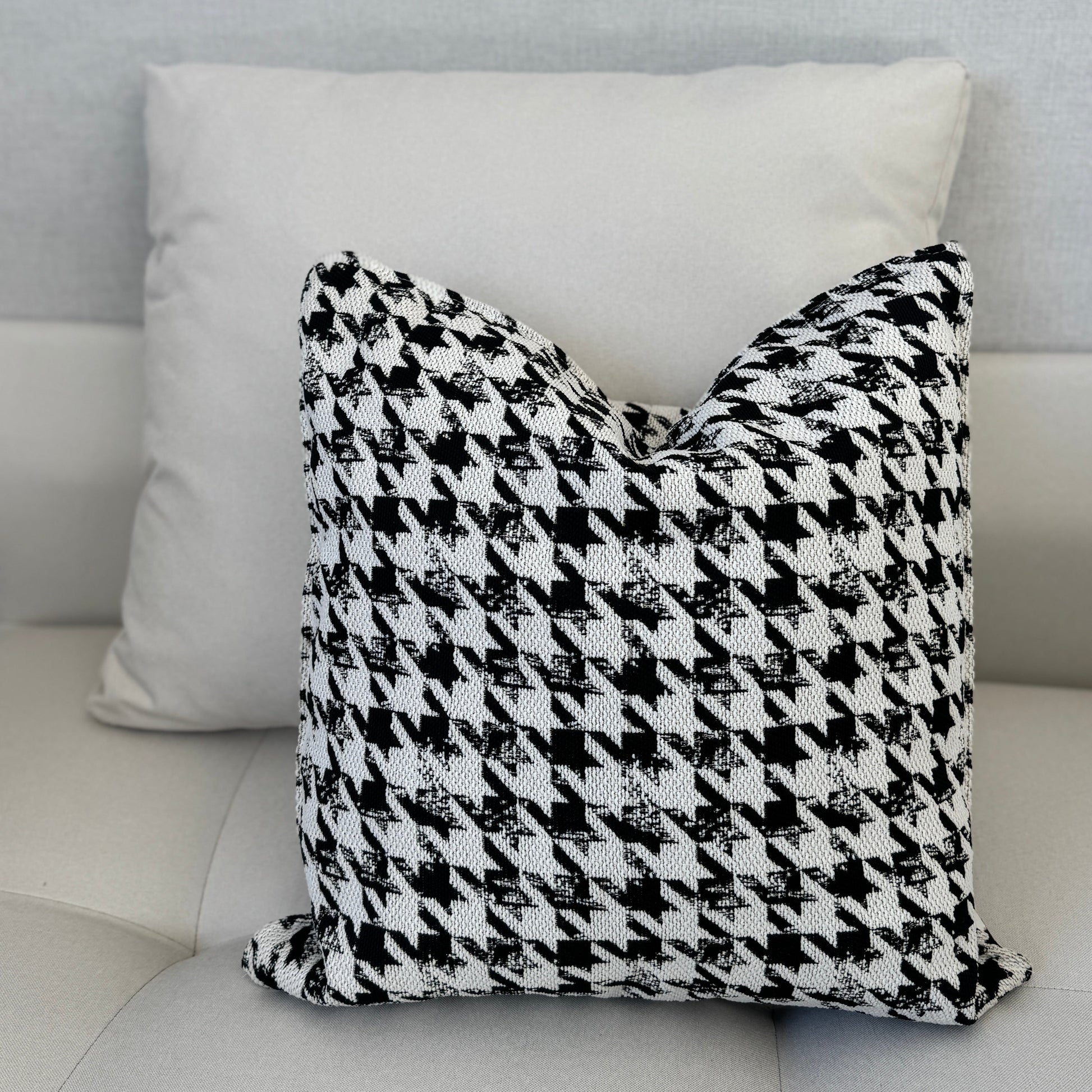 Coussin décoratif noir et blanc à motif pied-de-poule, tissu texturé tissé en relief, posé sur canapé moderne dans une ambiance épurée – Biyadi Collection