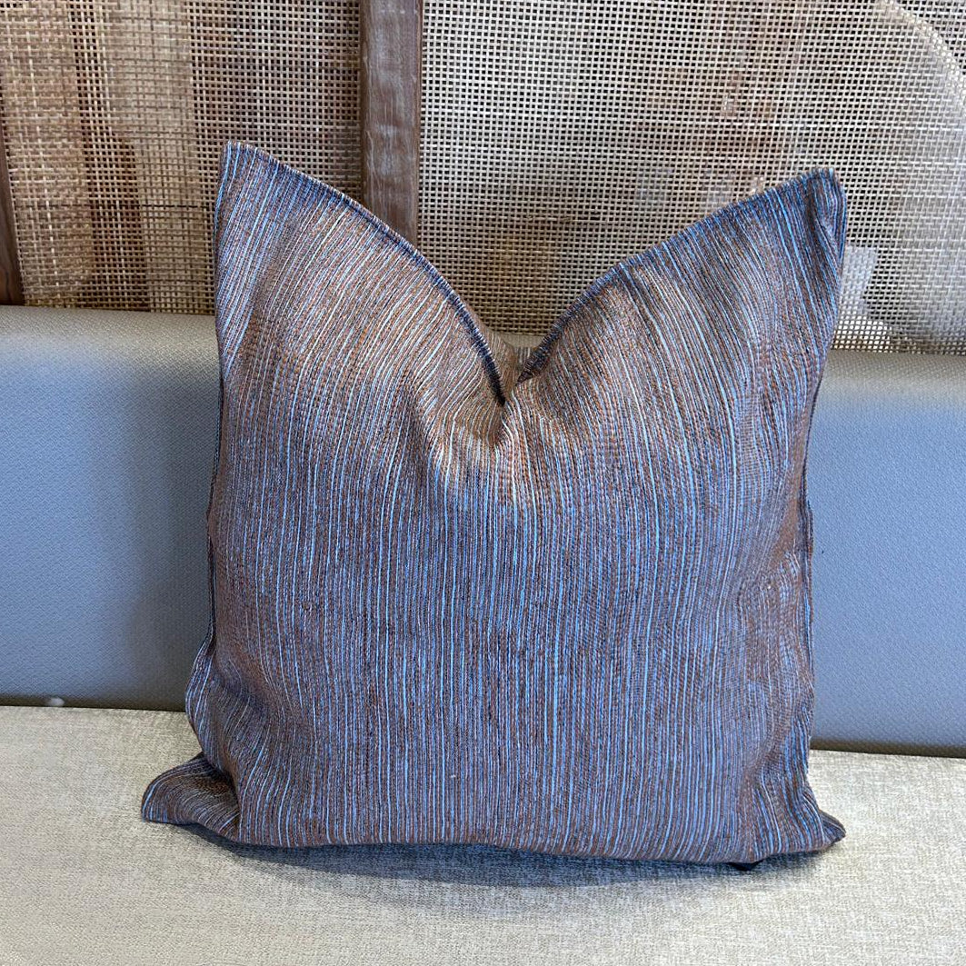 Coussin décoratif à fines rayures bleu et tons terre en tissu marocain, tissage délicat et finition élégante.