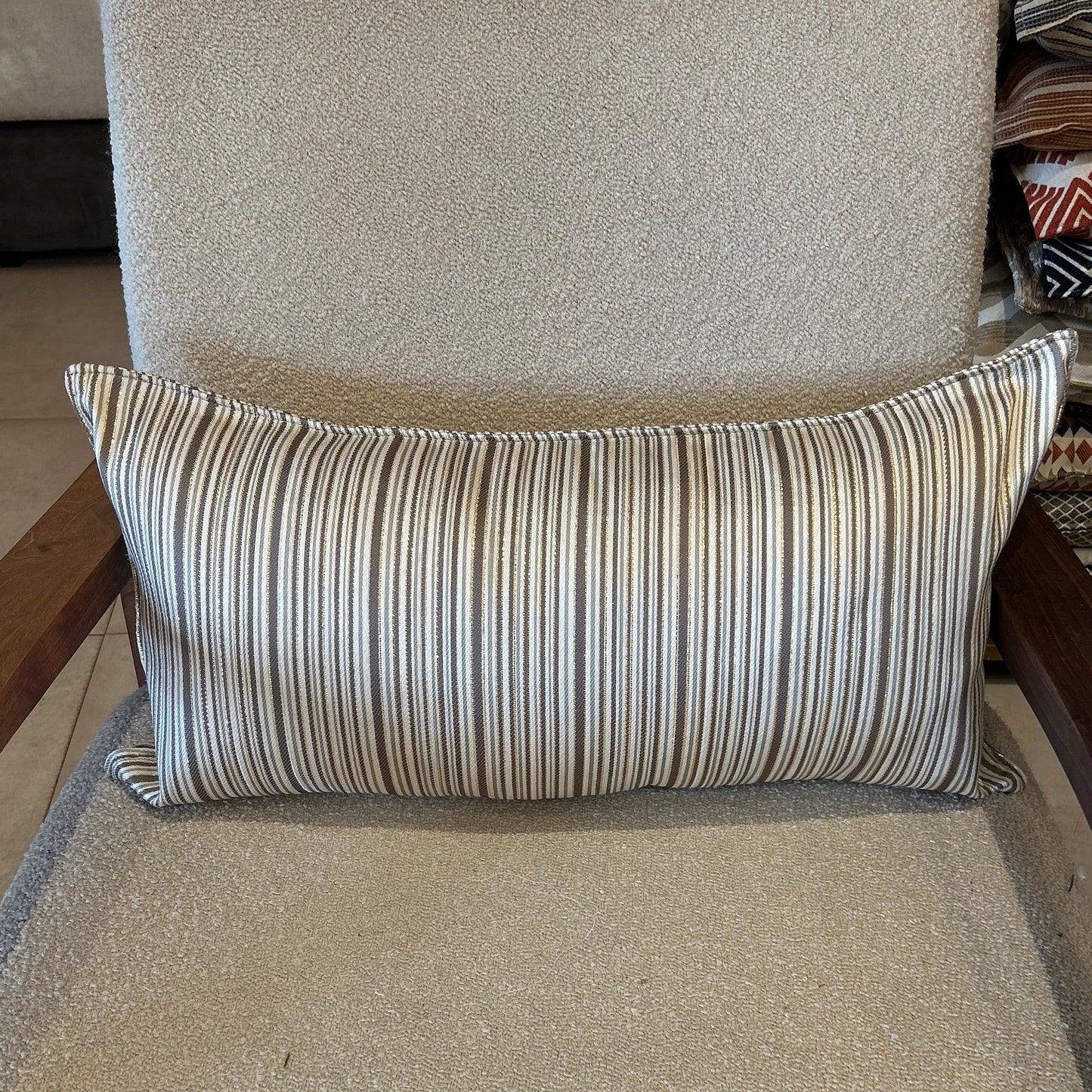 Détail d’un coussin rectangulaire à rayures taupe et écru, tissu texturé avec léger effet lumineux