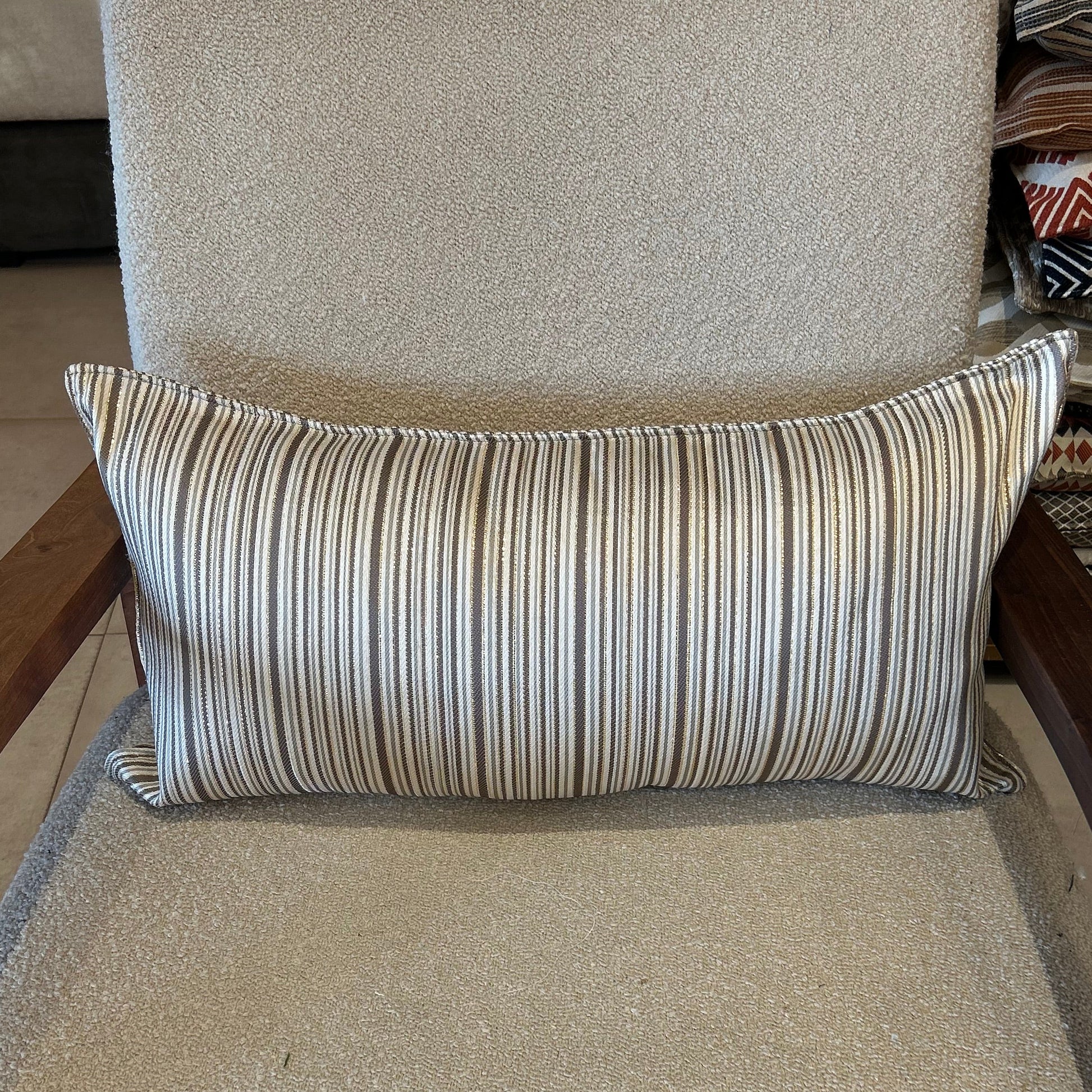 Détail d’un coussin rectangulaire à rayures taupe et écru, tissu texturé avec léger effet lumineux
