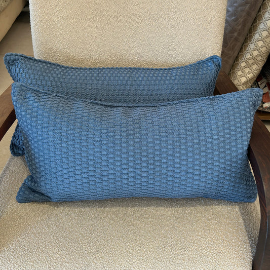 Coussin rectangulaire bleu à texture tissée en relief, coussin décoratif moderne posé sur fauteuil en tissu bouclette.