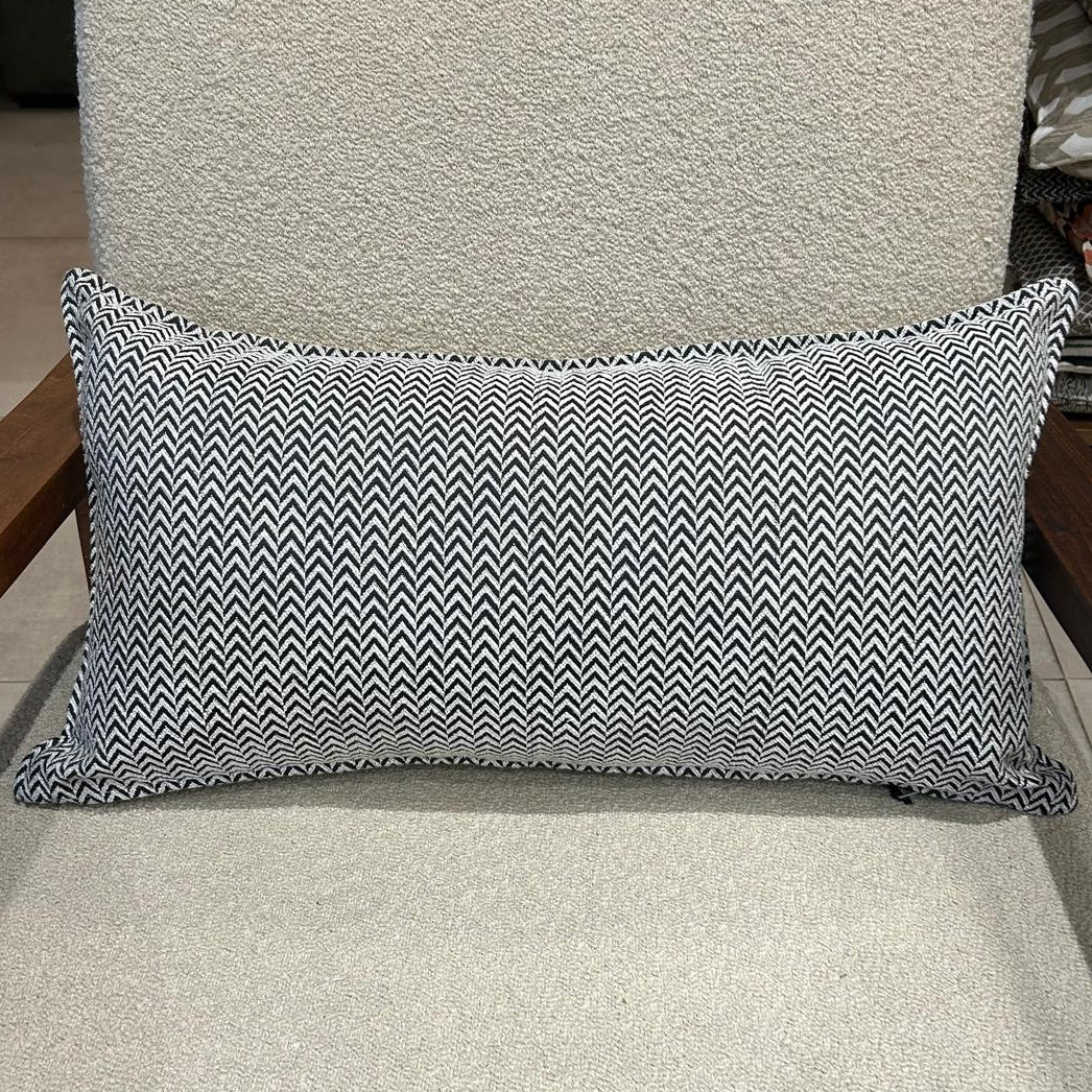 Coussin rectangulaire à motif chevron noir et blanc, en tissu texturé, posé sur fauteuil clair