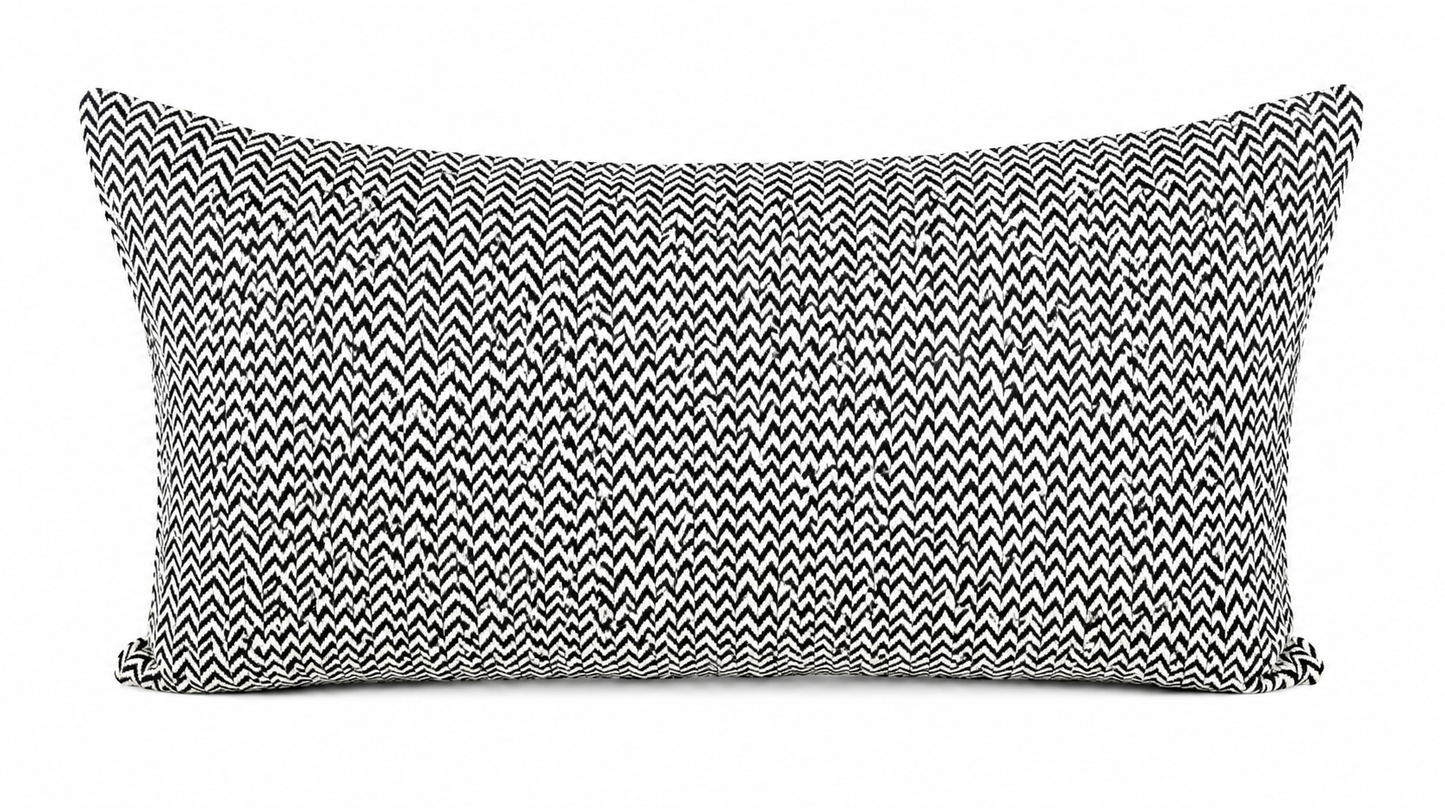 Coussin rectangulaire noir et blanc à motif chevron graphique, style moderne et minimaliste avec tissu texturé pour décoration élégante de salon.
