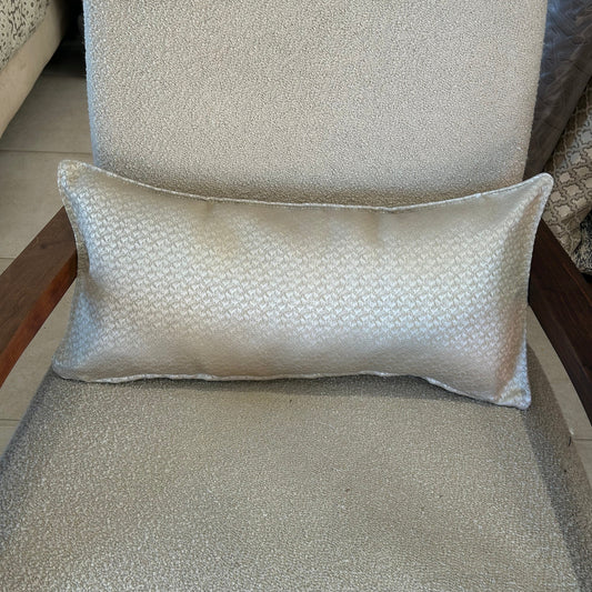 Coussin rectangulaire écru à motif discret, tissu élégant et raffiné, posé sur un fauteuil clair