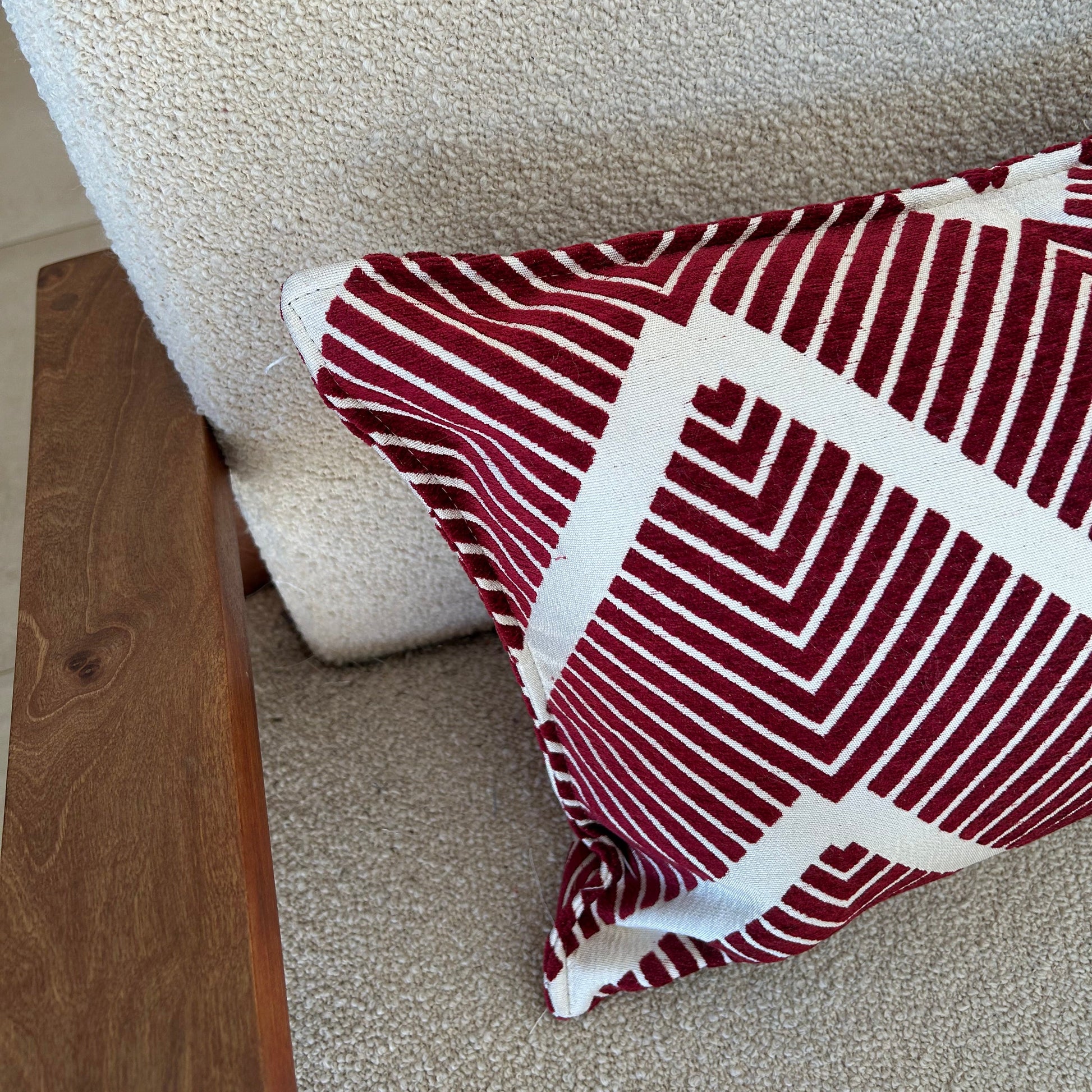 Detail d'un coussin rectangulaire décoratif bordeaux et écru à motif graphique en chevrons