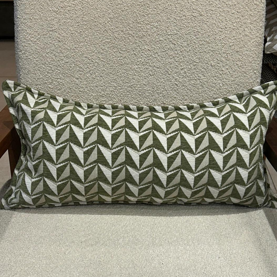 Coussin rectangulaire à motif géométrique vert et écru en tissu texturé, posé sur fauteuil clair