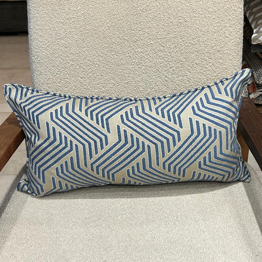 Coussin rectangulaire à motif graphique bleu et écru en tissu texturé, posé sur fauteuil clair