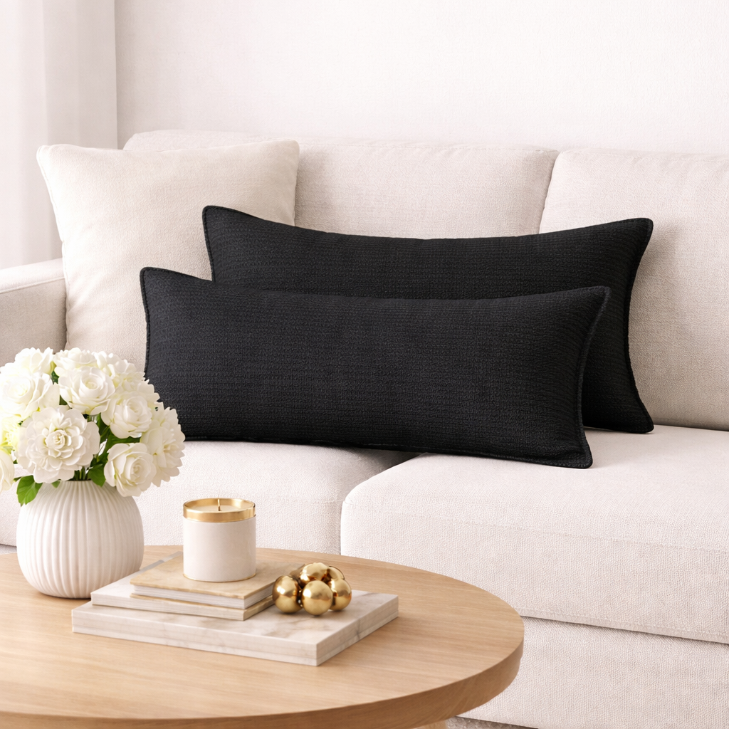 Coussins rectangulaires noirs unis tissés, disposés sur un canapé clair dans une ambiance moderne et élégante .