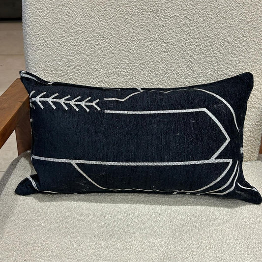 Coussin rectangulaire noir à motif graphique blanc en tissu texturé, posé sur fauteuil clair
